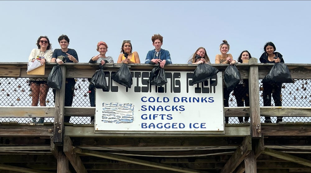 Stephen Decatur High School Surfrider Club holding trash that they collected at a Surfrider beach cleanup